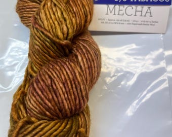 May include: A skein of brown, orange, and green yarn with a label that reads "878 TABACOS MECHA".
