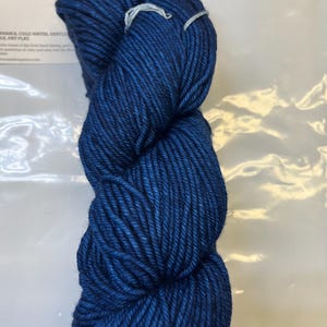 May include: A skein of deep blue yarn. The yarn is soft and smooth, and it is perfect for knitting or crocheting.