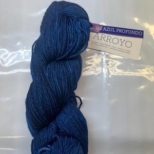 May include: A skein of deep blue yarn labeled "150 Azul Profundo Arroyo".