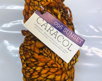 Puede incluir: Un ovillo de hilo super bulky naranja y negro llamado "Caracol" en el color "096 Sunset". El hilo es 100% lana merino superwash y tiene aproximadamente 87 metros (90 yardas) de largo.
