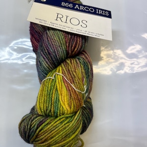Puede incluir: Un ovillo de hilo Rios 866 Arco Iris en un degradado multicolor de morado, verde, amarillo y rojo. El hilo es 100% lana merino superwash y tiene aproximadamente 210 yardas (192 metros) de largo.