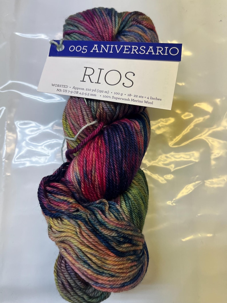 Puede incluir: Ovillo de lana Rios de grosor worsted en una vibrante mezcla de colores, incluyendo rosa, azul, verde y amarillo. La etiqueta dice "005 ANIVERSARIO" y "RIOS". La lana es 100% lana merino superwash. Aproximadamente 192 metros.