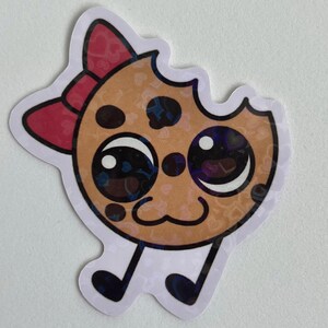 May include: A cartoon cookie with a big bite taken out of it. The cookie has big eyes, a cute smile, and a red bow on top. The cookie is brown with chocolate chips and is standing on two little legs.