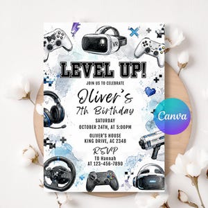 May include: A rectangular birthday invitation card featuring watercolor blue and gray splashes, gaming controllers, a VR headset, a racing wheel, and a toy blaster. The text reads LEVEL UP! JOIN US TO CELEBRATE Oliver's 7th Birthday OCTOBER 24TH, AT 5:00PM.