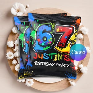 May include: Two black snack bags featuring a colorful paint splatter design, the number 67 in blue and red, and the text Justin's Birthday Party in multi-colored letters. The bags are decorated with cartoon hands holding the numbers.