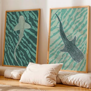 Può includere: Due stampe artistiche incorniciate con illustrazioni di vita marina. Una mostra una creatura simile a uno squalo, l'altra uno squalo balena. Entrambe nei toni del verde e del verde acqua, su uno sfondo a strisce zebrate.