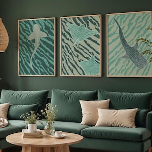 May include: Three framed art prints featuring marine life, including a shark and stingrays, against a teal and green zebra-striped background. The artwork hangs above a green sofa with beige pillows, creating a cohesive and stylish living room decor.