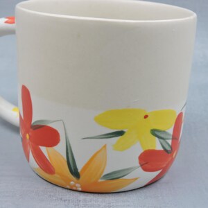 Puede incluir: Taza de cer&aacute;mica color crema con un dise&ntilde;o floral pintado a mano en rojo, amarillo y naranja, con hojas verdes. El asa tambi&eacute;n est&aacute; decorada con flores. Una taza decorativa para bebidas calientes.