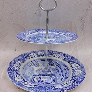 May include: Two-tiered cake stand with a silver metal stand and blue and white porcelain plates. The plates feature a traditional blue and white floral pattern.