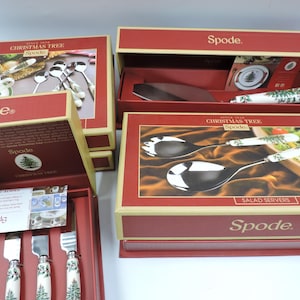 May include: Four boxes of Spode Christmas Tree dinnerware. The boxes are red with gold trim and feature images of the dinnerware. The boxes contain a set of salad servers, a set of teaspoons, a set of butter knives, and a cake server.