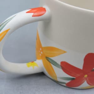 Puede incluir: Taza de cer&aacute;mica color crema con un asa grande, adornada con dise&ntilde;os florales pintados a mano en naranja, rojo y amarillo, con hojas verdes. Una pieza decorativa y alegre para disfrutar de bebidas.
