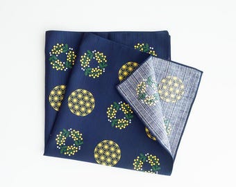 May include: Navy blue handkerchief with a repeating pattern of yellow and white floral wreaths and geometric starburst designs. The handkerchief is folded, revealing the patterned interior.