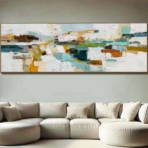 Puede incluir: Pintura abstracta de paisaje con marco dorado. La obra presenta una mezcla de colores, incluyendo blanco, azul, verde y marrón, creando un efecto texturizado. La pintura se exhibe sobre un sofá seccional color crema y una alfombra redonda.