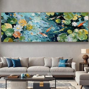 Puede incluir: Una pintura al óleo representa una escena de estanque con peces koi, nenúfares y flores de loto. La obra de arte presenta una paleta de azules, verdes, naranjas y amarillos. La pintura está enmarcada en un marco dorado y cuelga sobre un sofá gris.