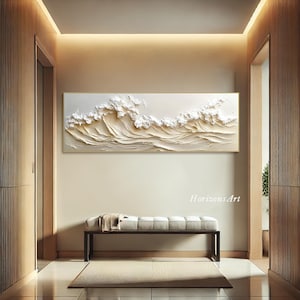 May include: A white and gold textured wall art piece depicting waves crashing. The art is framed in a thin gold frame and hangs on a wall in a modern home interior. The text "HorizonsArt" is visible in the bottom right corner of the image.