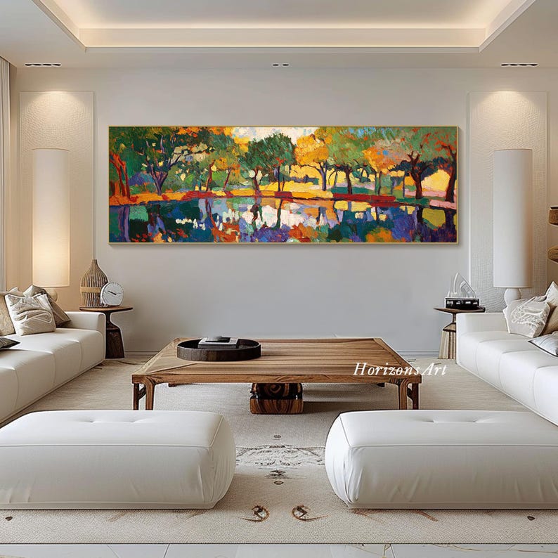 May include: A colorful abstract painting of a landscape with trees reflected in a still body of water. The painting is framed in gold and hangs on a white wall in a living room setting.