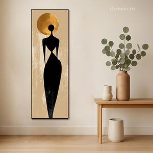 Puede incluir: Impresi&oacute;n art&iacute;stica abstracta que presenta una silueta negra de una figura con un halo dorado sobre un fondo beige texturizado. La obra de arte est&aacute; enmarcada en negro y tiene forma rectangular vertical. La obra se titula "Horizons Art".