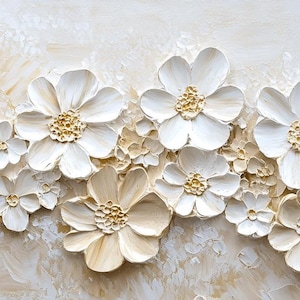 K&ouml;nnte beinhalten: Eine Wanddekoration mit einer Ansammlung von wei&szlig;en und goldenen 3D-Blumen mit einer strukturierten Oberfl&auml;che. Die Blumen sind in einer horizontalen Reihe angeordnet und vor einem hellbeigen Hintergrund platziert.
