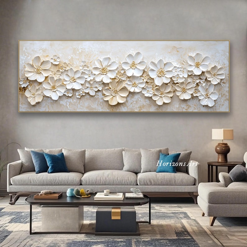 K&ouml;nnte beinhalten: Ein gro&szlig;es, rechteckiges Leinwandbild mit einem wei&szlig;en und goldenen Blumendesign. Die Blumen sind erhaben und strukturiert, was dem Bild einen 3D-Effekt verleiht. Der Hintergrund ist hellbeige.