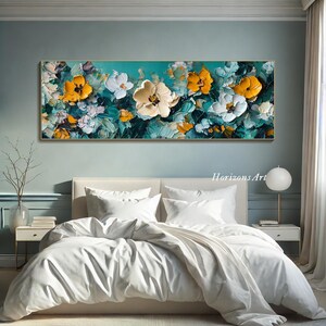 May include: Abstract painting of yellow and white flowers on a teal background. The painting is framed and hanging on a wall above a white bed with white bedding.