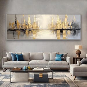 Puede incluir: Pintura abstracta de una ciudad con acentos dorados. La pintura es de estilo moderno y presenta un reflejo de la ciudad en el agua. La pintura est&aacute; colgada en una pared en un sal&oacute;n.