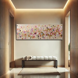 May include: Abstract floral painting in a rectangular format. The artwork features a beige background with colorful brushstrokes in pink, gold, and blue. The painting is framed in a black border and hangs above a bench.