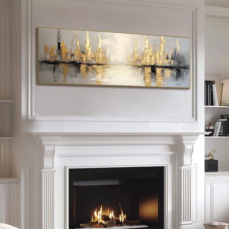 Puede incluir: Una pintura abstracta horizontal larga de un paisaje urbano con tonos dorados y grises. La pintura representa un horizonte urbano reflejado en una masa de agua. La pintura est&aacute; enmarcada y colgada en una pared blanca sobre una chimenea.