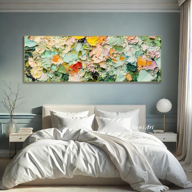 May include: Abstract painting with a textured, impasto style. The painting features a mix of green, pink, yellow, and white colors. The painting is displayed above a white bed with white bedding.