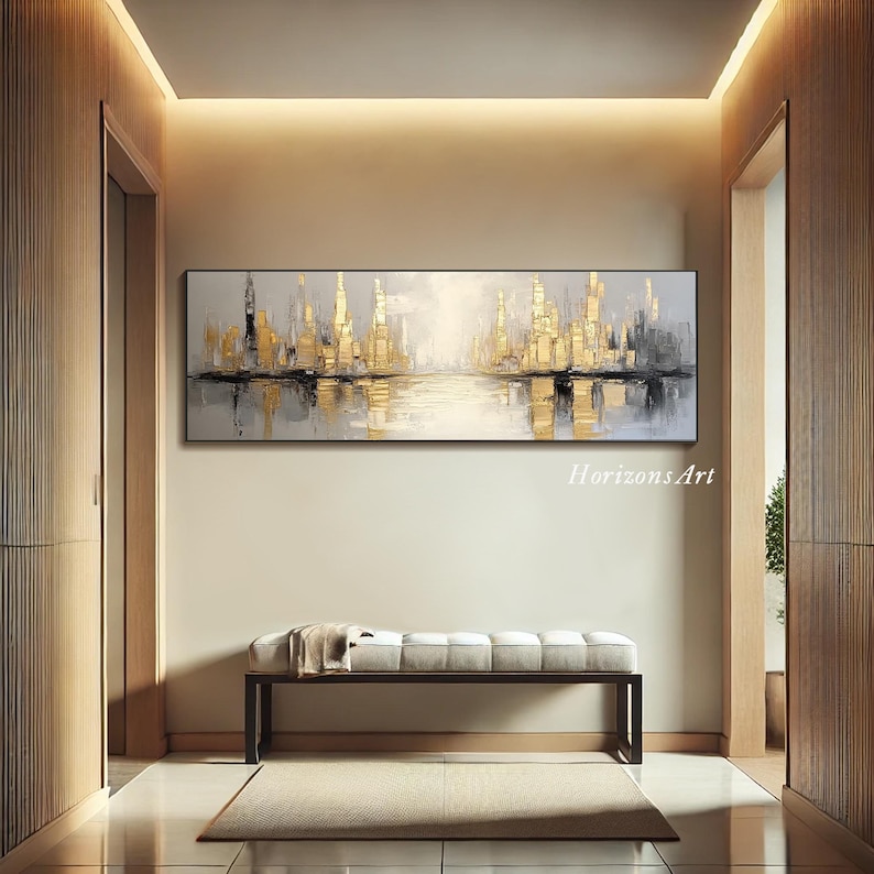 Puede incluir: Pintura abstracta de paisaje urbano en tonos dorados y grises. La pintura representa un horizonte urbano con edificios reflejados en una masa de agua. La pintura est&aacute; enmarcada y colgada en una pared de un pasillo.