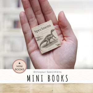 May include: A miniature book titled "Specimens" featuring dinosaur illustrations. The book is held in a hand, with the text "4 Mini Books" and "Mini Books" displayed. The book has a vintage aesthetic.