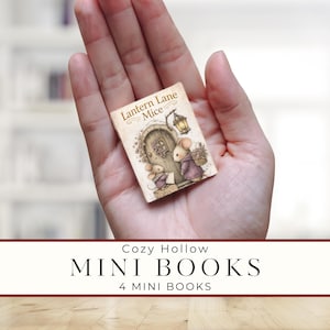Peut inclure: Un mini-livre intitulé "Lantern Lane Mice" avec une illustration de souris devant une porte. Le livre est tenu dans une main. En dessous, le texte indique "Cozy Hollow MINI BOOKS 4 MINI BOOKS".