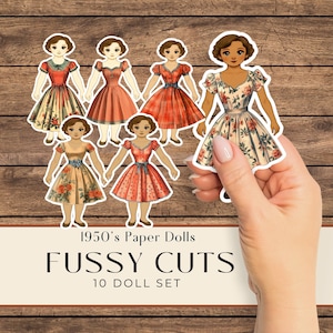 May include: A collection of 1950s paper doll cutouts featuring various dresses with floral and patterned designs. The dolls are held against a wooden background. Text on the image reads "1950's Paper Dolls", "FUSSY CUTS", and "10 DOLL SET".
