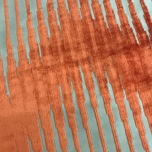 May include: A fabric with a textured pattern of vertical stripes in a light blue and orange colour combination.