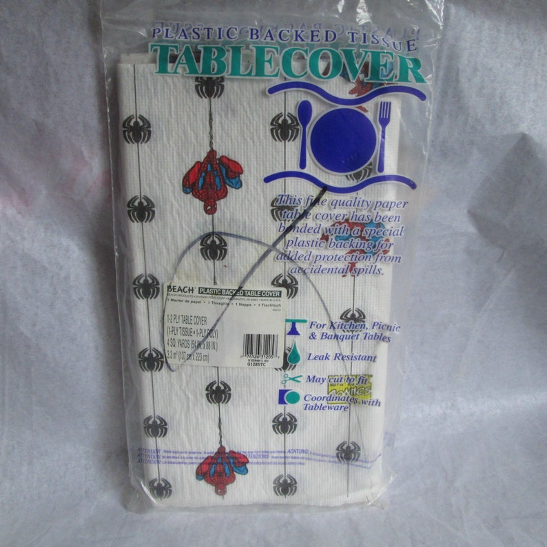 May include: A package of white plastic-backed paper table cover. The table cover has a pattern of black spiders and red and blue Spider-Man figures. The packaging includes text that reads "Plastic Backed Tissue Tablecover".
