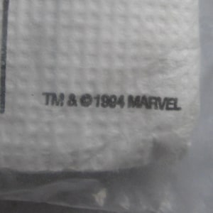 May include: Close-up of a white, textured surface with the text "TM & &copy; 1994 MARVEL" printed in black. The image is slightly out of focus, suggesting it is a detail of a larger item.