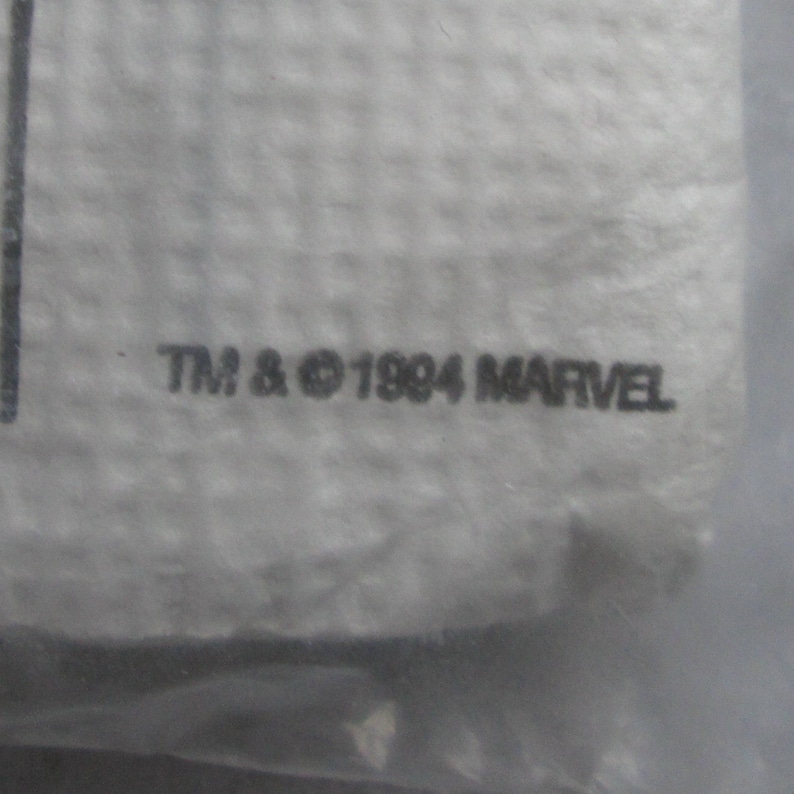 May include: Close-up of a white, textured surface with the text "TM & &copy; 1994 MARVEL" printed in black. The image is slightly out of focus, suggesting it is a detail of a larger item.