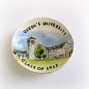 May include: A white ceramic dish with a watercolor painting of Queen's University. The dish has the words "Queen's University" and "Class of 2017" written on it.