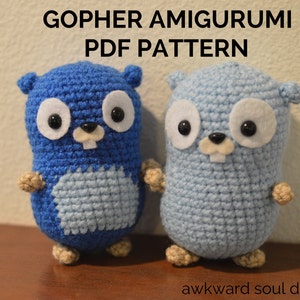 Könnte beinhalten: Zwei gehäkelte Amigurumi-Gophers, einer blau und einer hellblau, mit schwarzen Augen und weißen Filz-Nasen. Die Gophers stehen auf einer Holzoberfläche. Der Text "GOPHER AMIGURUMI PDF PATTERN" befindet sich über den Gophers.