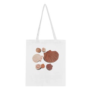 Pode incluir: Um saco tote branco com um gráfico impresso de seis conchas de diferentes tipos em tons de bege, castanho e areia. As conchas estão dispostas num grupo na parte frontal do saco, que possui duas alças compridas de tecido branco.