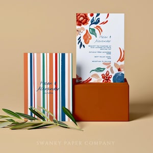 May include: Wedding stationery set with floral watercolour designs and striped patterns. The invitation cards display the names "Helen & Alexander" and event details. A sprig of greenery adds a natural touch. The colour palette includes orange, blue, and green.