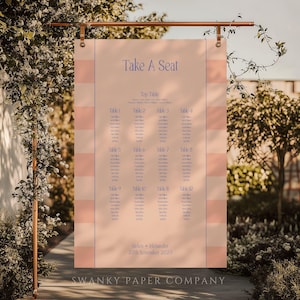 May include: A blush pink and white striped seating chart with the words "Take A Seat" in blue script. The chart lists table numbers and names, with the names "Belen + Alexander" and the date "27th November 2021" at the bottom. The Swanky Paper Company logo is at the bottom.