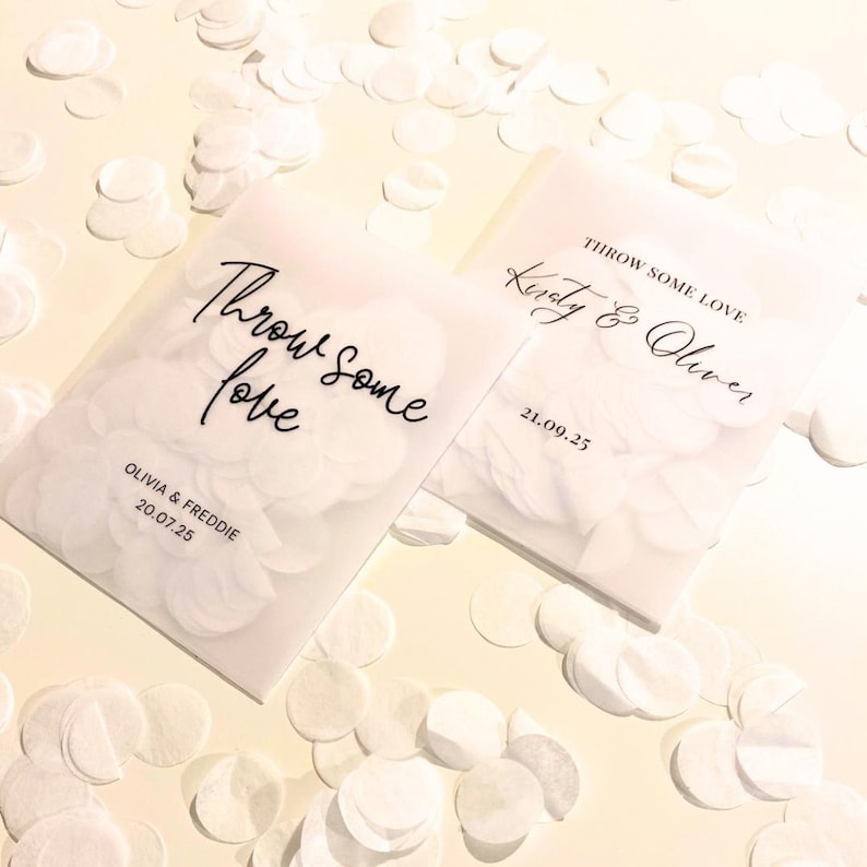 Op de afbeelding: Twee transparante zakjes gevuld met witte confetti. Op &eacute;&eacute;n staat "Throw some love" in sierlijke letters, met de namen "Olivia & Freddie 20.07.25". De andere toont "Kirsty & Oliver 21.09.25". Witte confetti is verspreid.