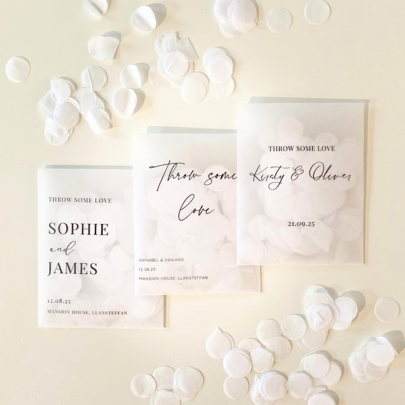 Op de afbeelding: Drie doorschijnende zakjes met witte confetti, elk met de tekst "Throw Some Love" en gepersonaliseerde namen en data. Witte confetti is verspreid rond de zakjes op een cr&egrave;mekleurige achtergrond.