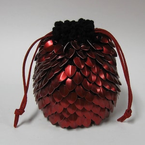 May include: Red metal dice bag with a black crocheted top and red drawstrings.
