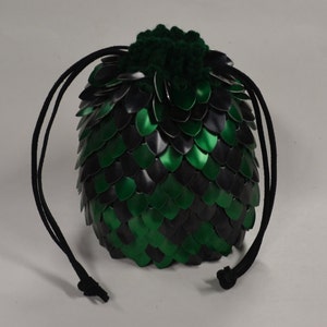 May include: A green and black chainmail dice bag with a green crocheted top and black drawstrings.