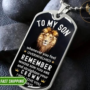 K&ouml;nnte beinhalten: Eine silberne Hundemarke mit schwarzem Hintergrund und einem L&ouml;wenbild. Der Text auf der Marke lautet "To My Son" und "Whenever you feel overwhelmed, remember whose son you are and straighten your crown. I will love you always."