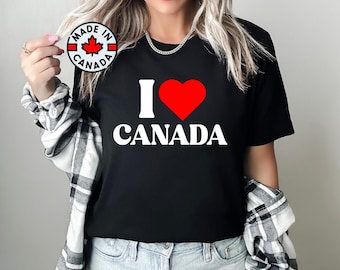 May include: Black t-shirt with a white "I love Canada" graphic featuring a red heart. The shirt also has a small red and white "Made in Canada" sticker with a maple leaf.