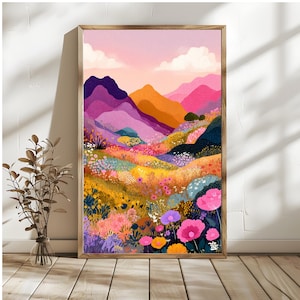 Könnte beinhalten: Ein gerahmter Kunstdruck mit einem farbenfrohen Landschaftsgemälde. Das Kunstwerk zeigt sanfte Hügel und Berge in Lila-, Orange- und Rosatönen, mit einem Vordergrund aus Wildblumen in Gelb, Rosa und Lila. Der Himmel ist ein zartes Rosa mit weißen Wolken.