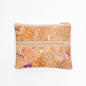 May include: A small, rectangular cork wallet with two zippered compartments. The wallet has a natural cork color with iridescent accents and star-shaped details. The zippers and trim are a matching beige color.