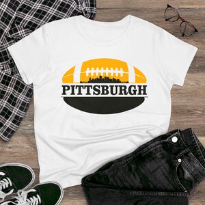 May include: White t-shirt with a black and yellow football graphic and the text "PITTSBURGH" printed on it.